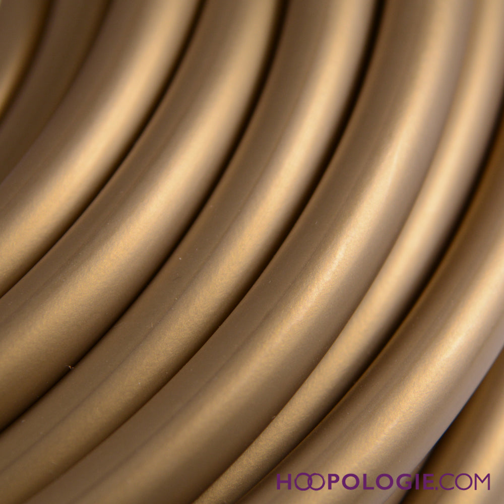 Close-up of gold HDPE hula hoop tubing showing smooth, flexible texture and warm metallic color.